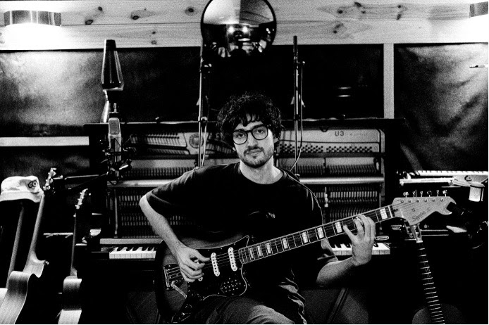 Alexander French seated with an electric guitar in a recording studio